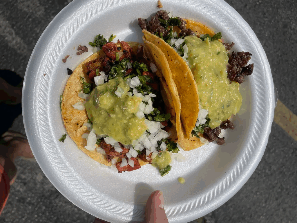 a styrofoam plate of two tacos, one carne asada and one al pastor