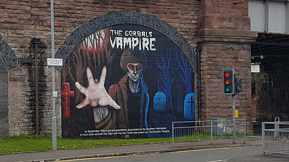 a mural painted on the side of a tunnel bridge with a teenaged-looking vampire with that swoopy haircut and red eyes reaching out at the viewer