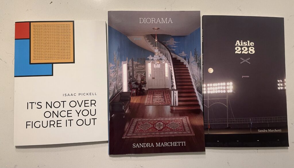 books, It's not over once you figure it out by Isaac Pickell, Diorama by Sandra Marchetti, and Aisle 228 by Sandra Marchetti