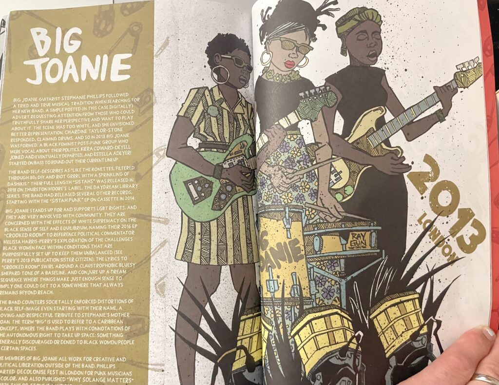 a page from a zine featuring a drawing of Big Joanie playing live, they are three Black women all standing up, even the drummer