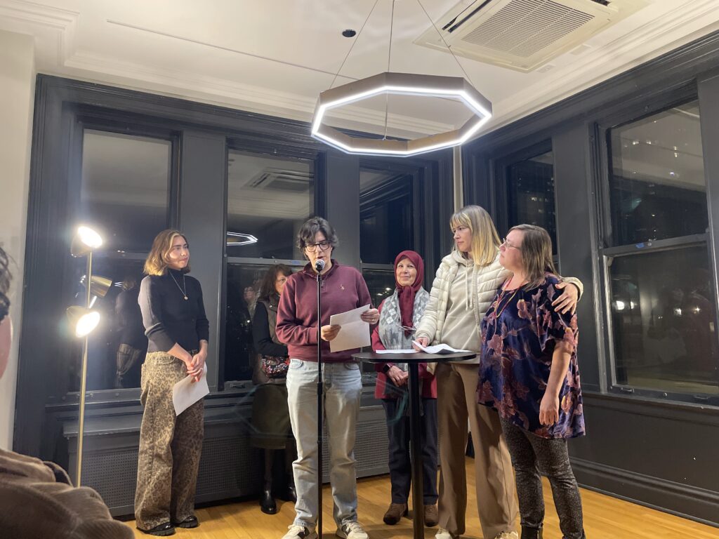 a collective of women poets, taking turns reading at a microphone