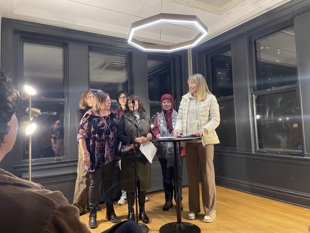 a collective of women poets, taking turns reading at a microphone