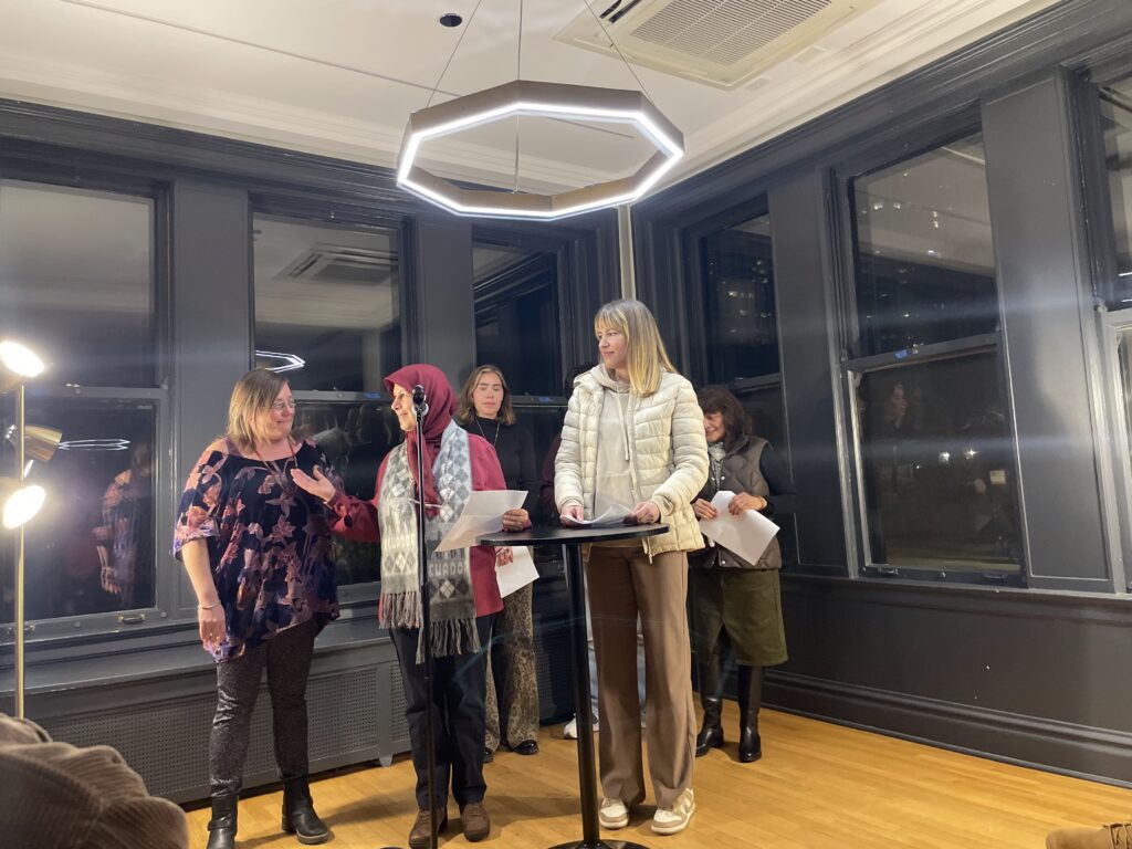 a collective of women poets, taking turns reading at a microphone