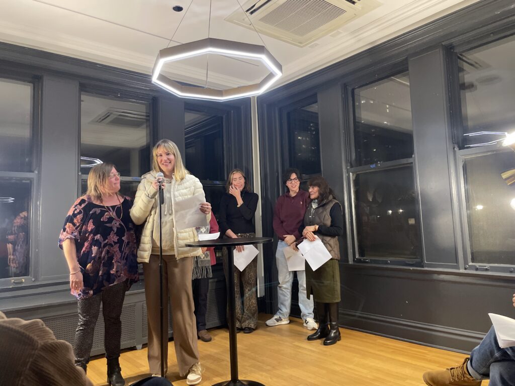 a collective of women poets, taking turns reading at a microphone