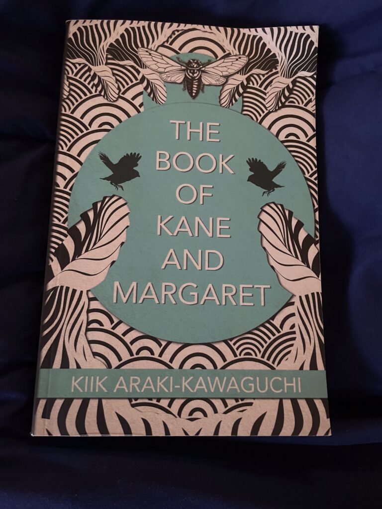 a book, The Book of Kane and Margaret by Kiik Araki-Kawaguchi, on a blanket