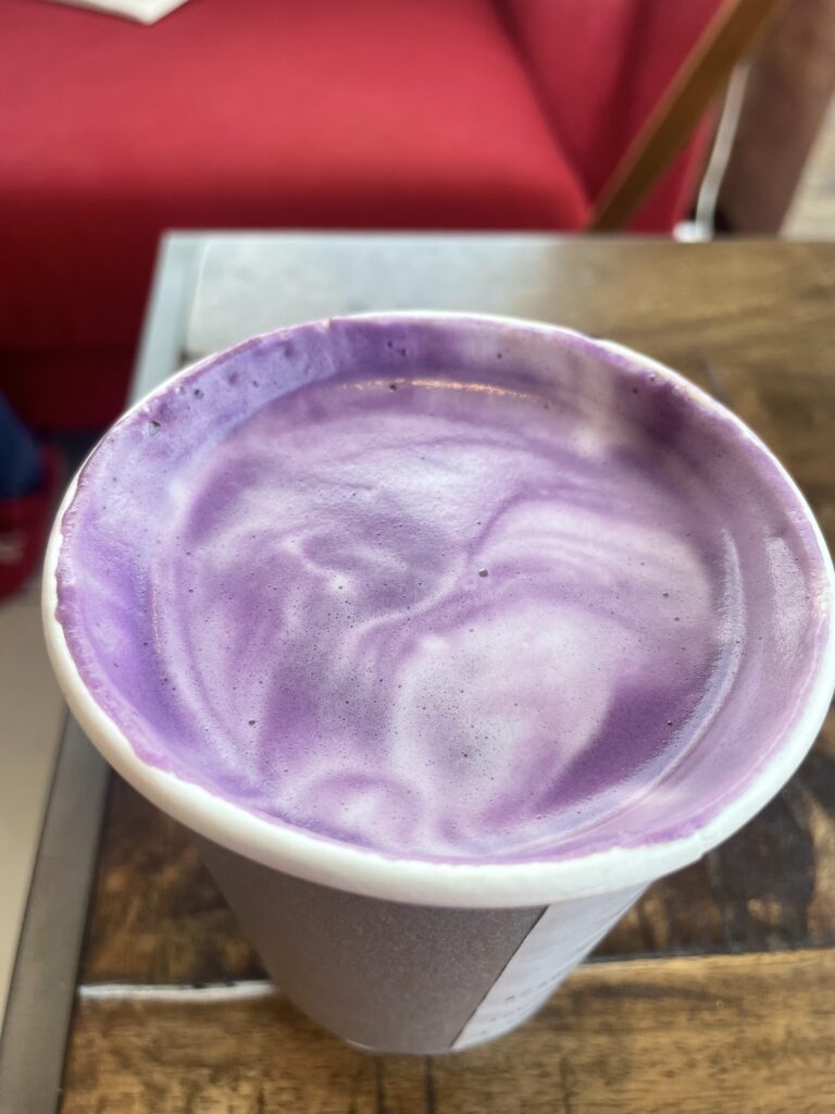 closeup of the purple and white swirls of an ube latte in a paper cup