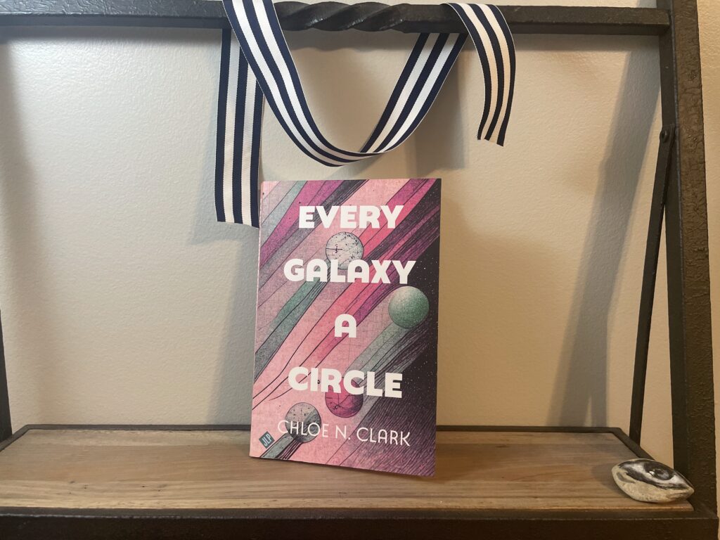 a book, Every Galaxy A Circle by Chloe N. Clark, on a shelf