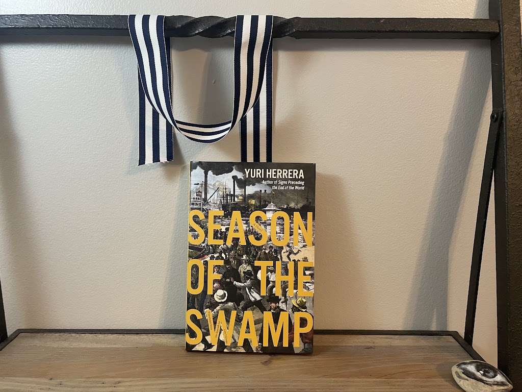 a book, SEASON OF THE SWAMP by Yuri Herrera, on a shelf