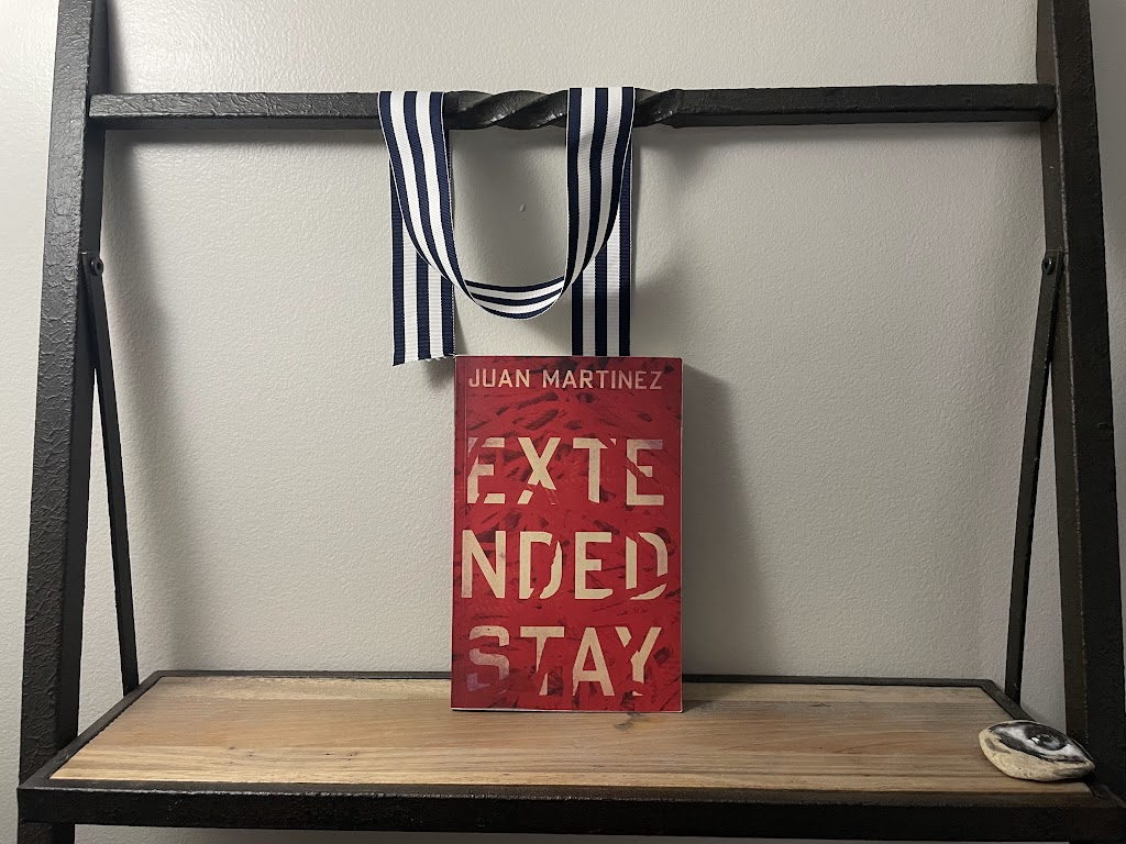 a book, EXTENDED STAY by Juan Martinez, on a shelf