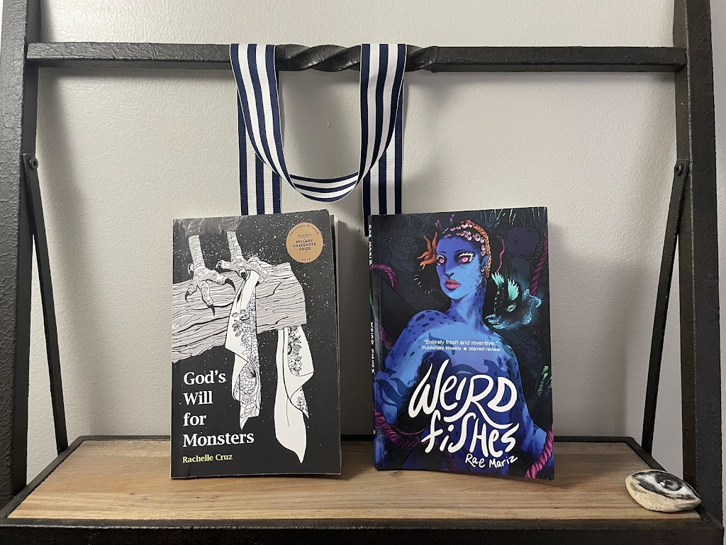 two books, God's Will For Monsters by Rachelle Cruz and Weird Fishes by Rae Mariz, on a shelf